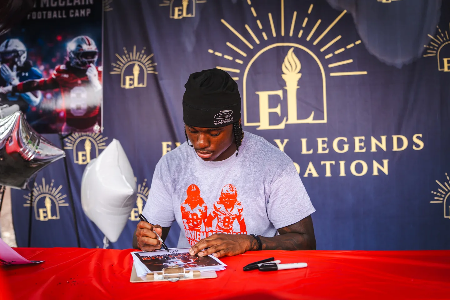 Jaylen McClain signs an autograph at the Everyday Legends Foundation table.