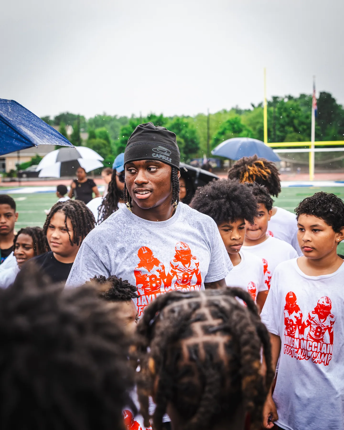 Jaylen McClain talks with campers gathered around him in the rain at the Jaylen McClain Youth Football Camp.