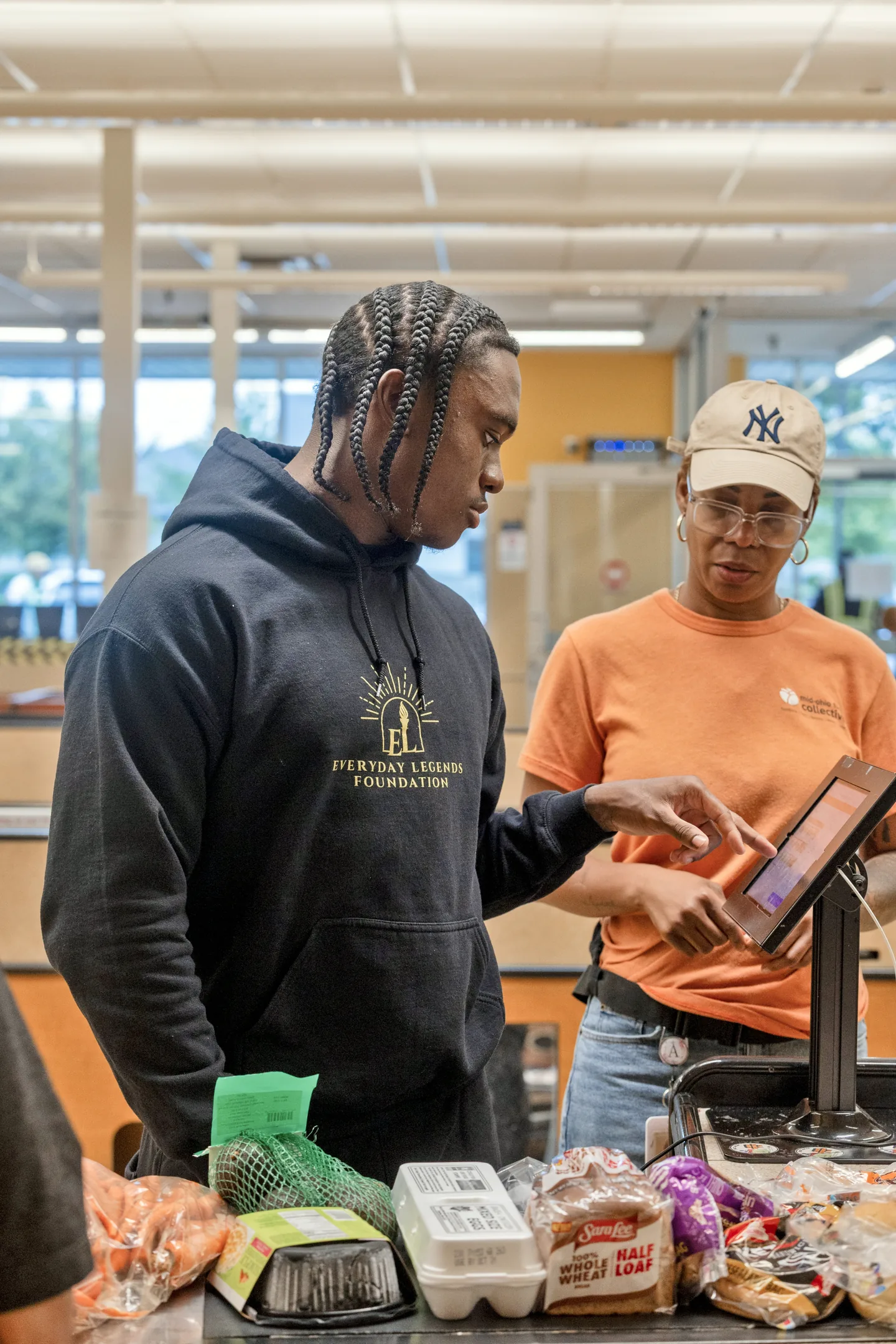 Jaylen McClain helps a shopper check out with her groceries at Mid-Ohio Market.