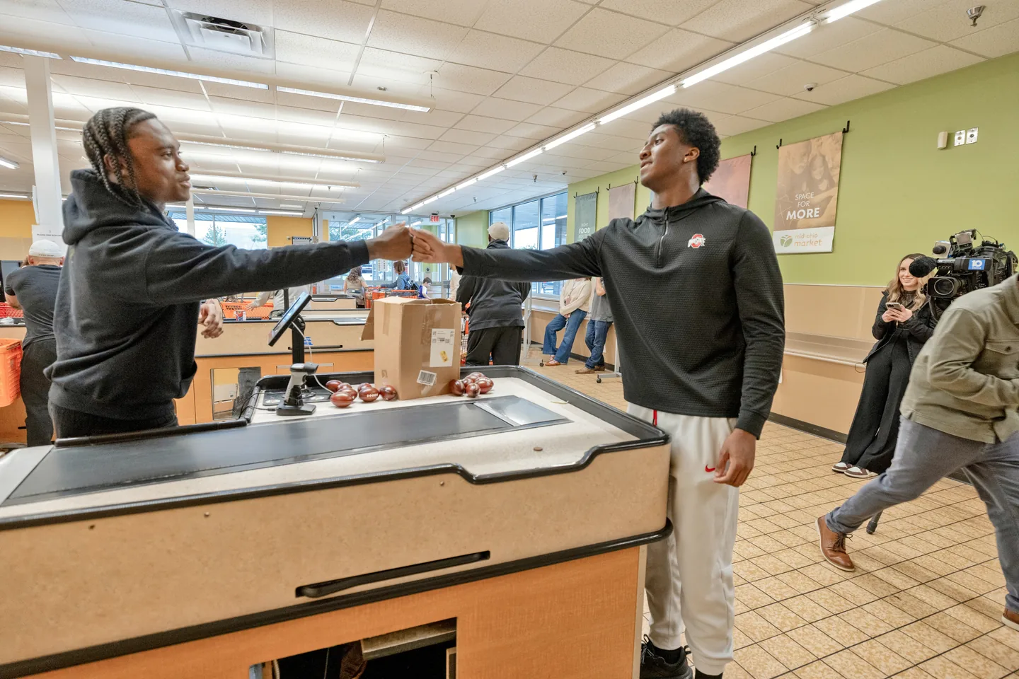 Jaylen McClain shares a fist bump with a shopper across the checkout counter at Mid-Ohio Market.