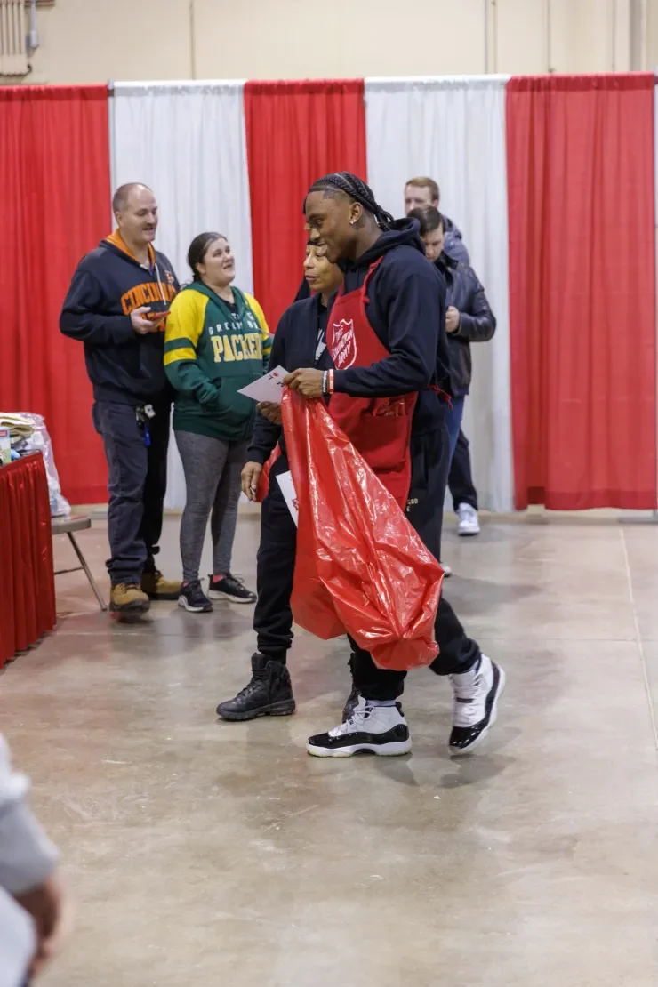 Jaylen McClain carries a bag of toys past volunteers at the Salvation Army toy drive.