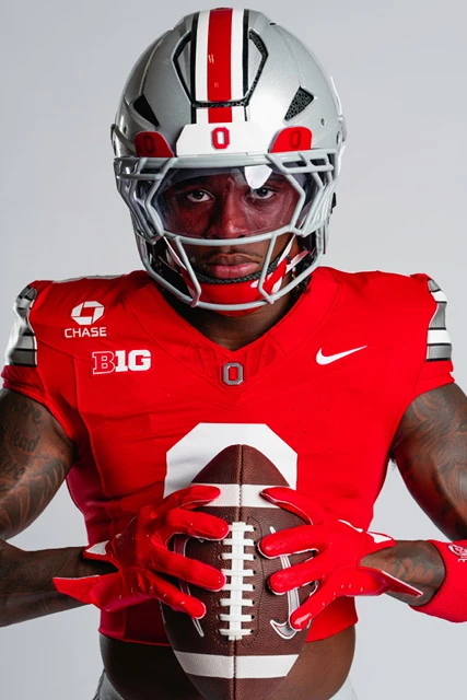 Jaylen McClain in his Ohio State jersey and helmet, holding a football, studio portrait.