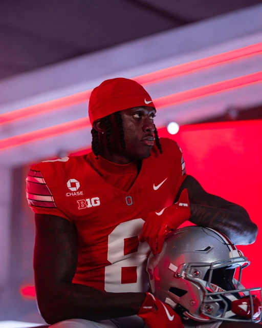 Jaylen McClain holding his helmet, lit in red, in the tunnel before a game.